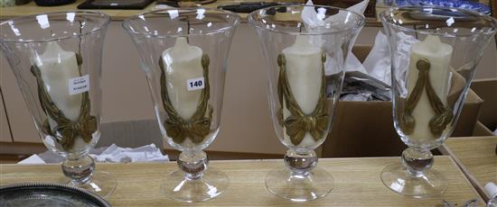 A set of four glass storm shades, with candles height 35cm